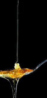 Golden honey dripping onto a spoon against a black background.