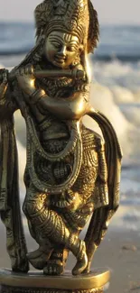 Golden Krishna statue with ocean background.