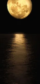 Golden moon casting reflection over calm ocean at night.