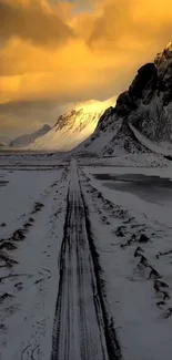 Golden-lit mountains with snow-covered road path.