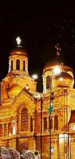 Golden illuminated cathedral at night with a starry sky backdrop.