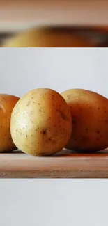 Golden potatoes on a wooden surface wallpaper.