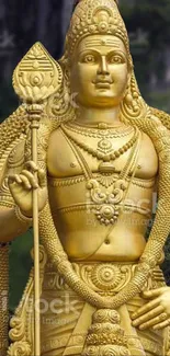 Intricate golden statue on lush green background, ideal for mobile wallpaper.