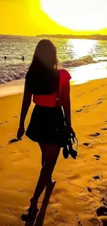 Woman walking on sandy beach at golden sunset.