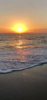 Golden sunset over ocean waves and sandy beach.