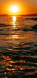 Golden sunset casting orange hues over a calm ocean horizon.