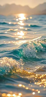 Golden sunset reflecting on ocean waves with distant mountains.