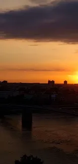 Golden sunset over a city skyline with silhouettes and an orange sky.