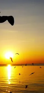 Golden sunset over ocean with birds flying.