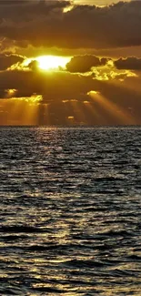 Golden sunset over ocean waves, sunbeams through clouds.