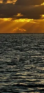 Golden sunset over ocean with shimmering water waves and cloudy sky.