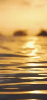 Golden sunset over calm water with ripples and silhouettes on the horizon.