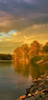 Golden sunset over a tranquil river with rocky banks and lush trees.