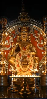 Golden deity statue lit with numerous candles creating a divine atmosphere.