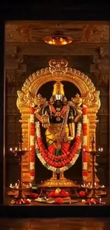 Golden deity statue inside a temple shrine with candles and garlands.