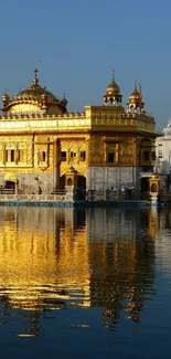 Golden Temple reflected on serene water, under a blue sky.