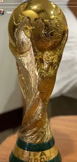 Golden world trophy on a wooden table, showcasing intricate details.