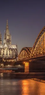 Gothic cathedral with illuminated bridge at dusk.