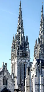 Gothic cathedral spires under a clear blue sky, showcasing historic architecture.