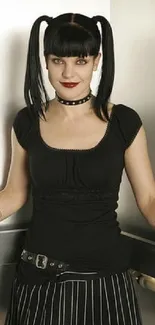 Person with black pigtails in gothic fashion, dark outfit, and studs.