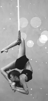 Grayscale artistic wallpaper of an aerial acrobat performing a pose.