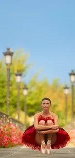 Ballerina in red tutu with flowers and lampposts outdoors.