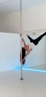 Dancer performing a graceful pole dance move in a bright studio.