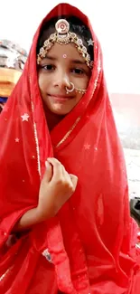 Young girl in vibrant red traditional attire, smiling gracefully.