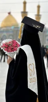 Person in hijab holding flowers during graduation.