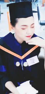 Graduate in blue and black regalia with closed eyes at ceremony.