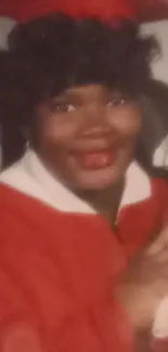 Smiling graduate in red cap and gown holding a diploma.