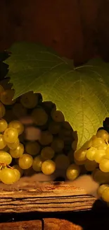 Cluster of green grapes with a large leaf on a rustic background.