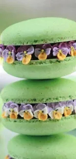 Stack of vibrant green macarons with purple and yellow floral decorations.