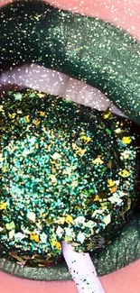 Close-up of lips with green glitter and lollipop.