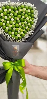 Heart-shaped green fruit bouquet with black wrap and green ribbon.