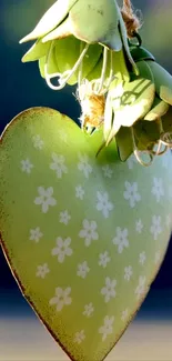 Green heart with floral design hanging on branch.