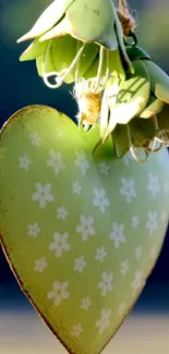 Green heart ornament with floral patterns against a blue backdrop.