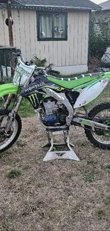 Green motocross bike on a stand in an outdoor setting.