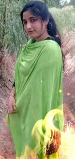 Woman in vibrant green scarf outdoors among natural scenery.