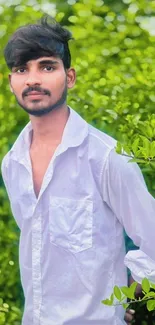 Young man in white shirt in lush green scenery.