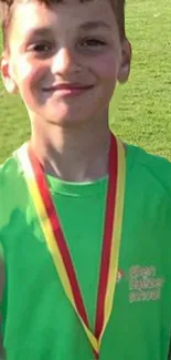 Young athlete smiling with medal in green shirt.