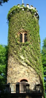 Stone tower with ivy surrounded by lush greenery under a clear blue sky.