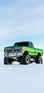 Green truck on snowy landscape under a bright blue sky.