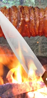 Grilled meat and knife amidst vibrant flames.