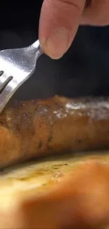 Close-up of juicy grilled sausage with fork on wooden board.