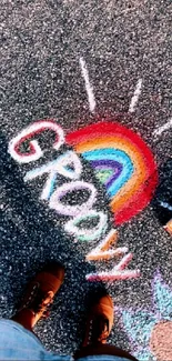 A colorful chalk drawing of a rainbow and 'GROOVY' on asphalt.