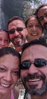 Group smiling in front of waterfall surrounded by nature.