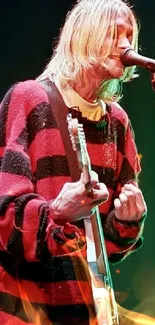 Grunge musician playing guitar in a red and black sweater on stage.