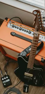 Electric guitar resting on amplifier on wooden floor.