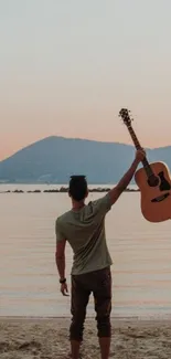 Person holding a guitar at a sunset beach.